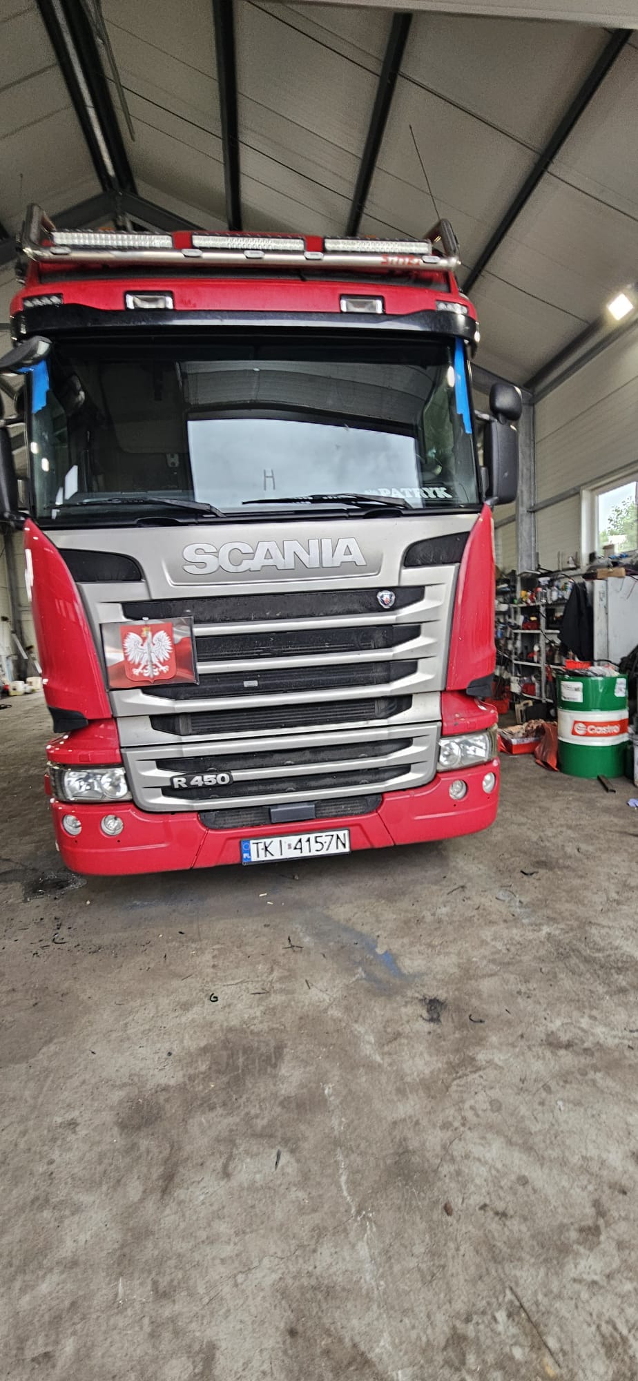 Scania R450 z nową szybą czołową zabezpieczoną taśmą w hali serwisowej